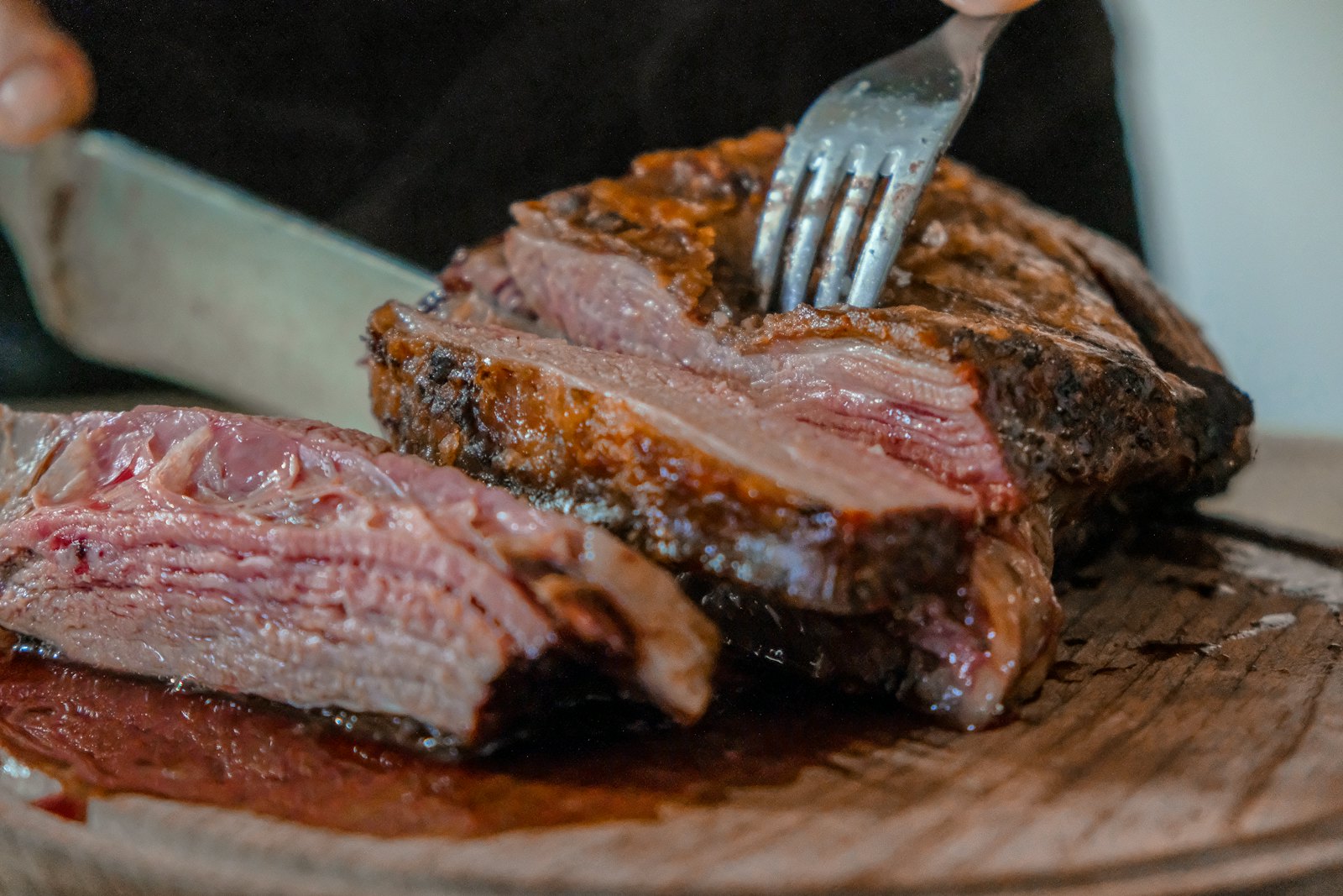 Carne assada sendo fatiada com garfo e faca